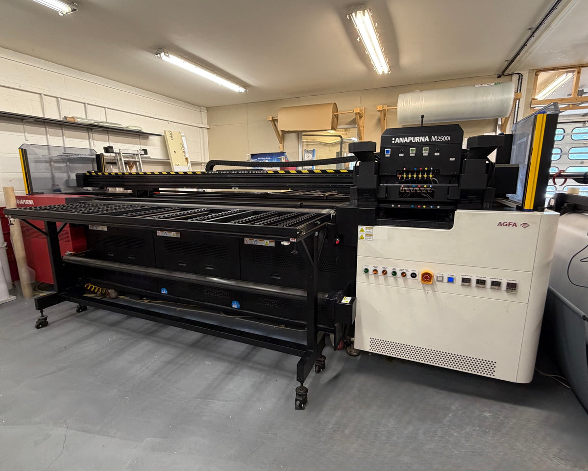 A large industrial flatbed UV printing machine, specifically a LANJIMA MV2000 with an AGFA scanner bed, photographed inside a workshop or garage environment with concrete floors and fluorescent lighting.